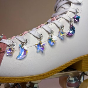 May include: White roller skates with iridescent crystal charms in the shape of stars, moons, and hearts attached to the laces.