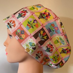 May include: A patterned cap with a patchwork design. The cap features floral motifs in various colours, including pink, green, yellow, and brown. The design creates a vibrant and eye-catching accessory.
