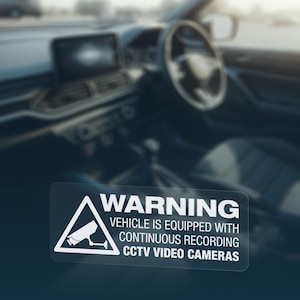 May include: White warning sticker with a black triangle and a camera icon. The text reads "WARNING VEHICLE IS EQUIPPED WITH CONTINUOUS RECORDING CCTV VIDEO CAMERAS".