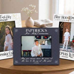 May include: Three framed photos on a wooden table. Each frame has a photo of a child and text that reads "First Holy Communion." The frames are black and white with decorative elements and the names and dates of the children.