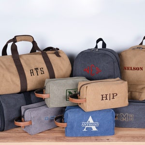 May include: A collection of eight personalized canvas bags in various colors and sizes. The bags feature embroidered initials and names, including "RTS", "WES", "NELSON", "HIP", "AMH", and "ANTHONY".