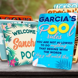 May include: Four colorful metal signs with tropical themes and text. The signs read "Jackson's", "Garcia's Pool Rules", "Welcome to Sancha's Pool", and "Pool Rules".