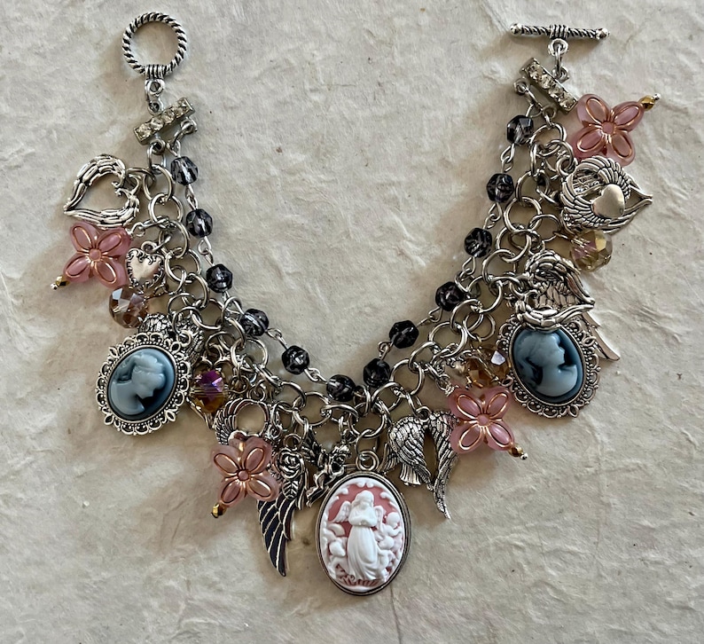 Puede incluir: Pulsera de plata con m&uacute;ltiples colgantes. La pulsera presenta colgantes de camafeo, dijes de flores rosas, dijes de alas de &aacute;ngel y dijes de coraz&oacute;n. La pulsera tiene un cierre de palanca y est&aacute; hecha de metal plateado y cuentas negras.