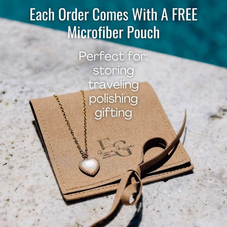 Puede incluir: Una bolsa de gamuza marr&oacute;n con una cadena dorada y un colgante en forma de coraz&oacute;n. La bolsa tiene una cinta atada alrededor y el texto "Each Order Comes With A FREE Microfiber Pouch Perfect for: storing traveling polishing gifting" est&aacute; impreso encima de la bolsa.