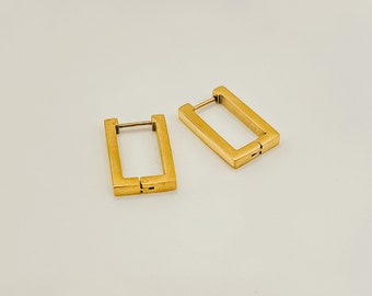 May include: Two gold-colored rectangular hoop earrings. The earrings have a simple, modern design with a hinged closure. The earrings are made of a shiny, metallic material and are displayed on a white surface.