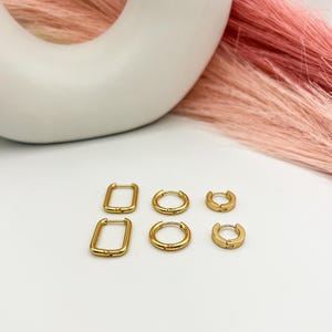 May include: Set of four gold hoop earrings, two are round and two are rectangular.