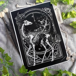 Könnte beinhalten: Eine Schwarzweißillustration eines Hirschskeletts mit floralen Details und einem Vogel, der auf einem Ast sitzt. Das Bild ist mit einem verzierten Design gerahmt.