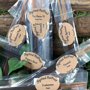 May include: A variety of incense sticks in clear plastic bags with brown labels. The labels have the text "Mystical OutPost" and the name of each scent. The scents are Cedarwood Sage, Dragon's Blood, Top Choice #3, Darkly Mysterious, Frankincense, and Fireweed.