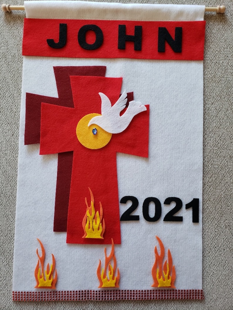 Pu&ograve; includere: Uno stendardo di feltro bianco con il nome "JOHN" in lettere nere in alto. Una croce rossa con una colomba bianca e un cerchio giallo &egrave; al centro. L'anno "2021" &egrave; in lettere nere sotto la croce. Ci sono tre fiamme arancioni nella parte inferiore dello stendardo.