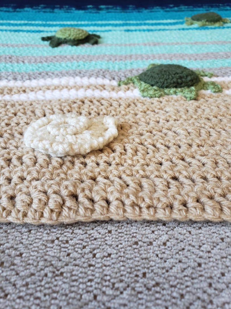 Peut inclure: Une sc&egrave;ne de plage en crochet avec un coquillage blanc, des tortues de mer vertes et des rayures bleues et blanches.