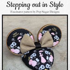 May include: A black and white fabric headband with a gold bow and a Mary Poppins inspired design. The headband is decorated with pink flowers and a silhouette of Mary Poppins holding an umbrella. The text "Mary Poppins" is written in gold on the headband.