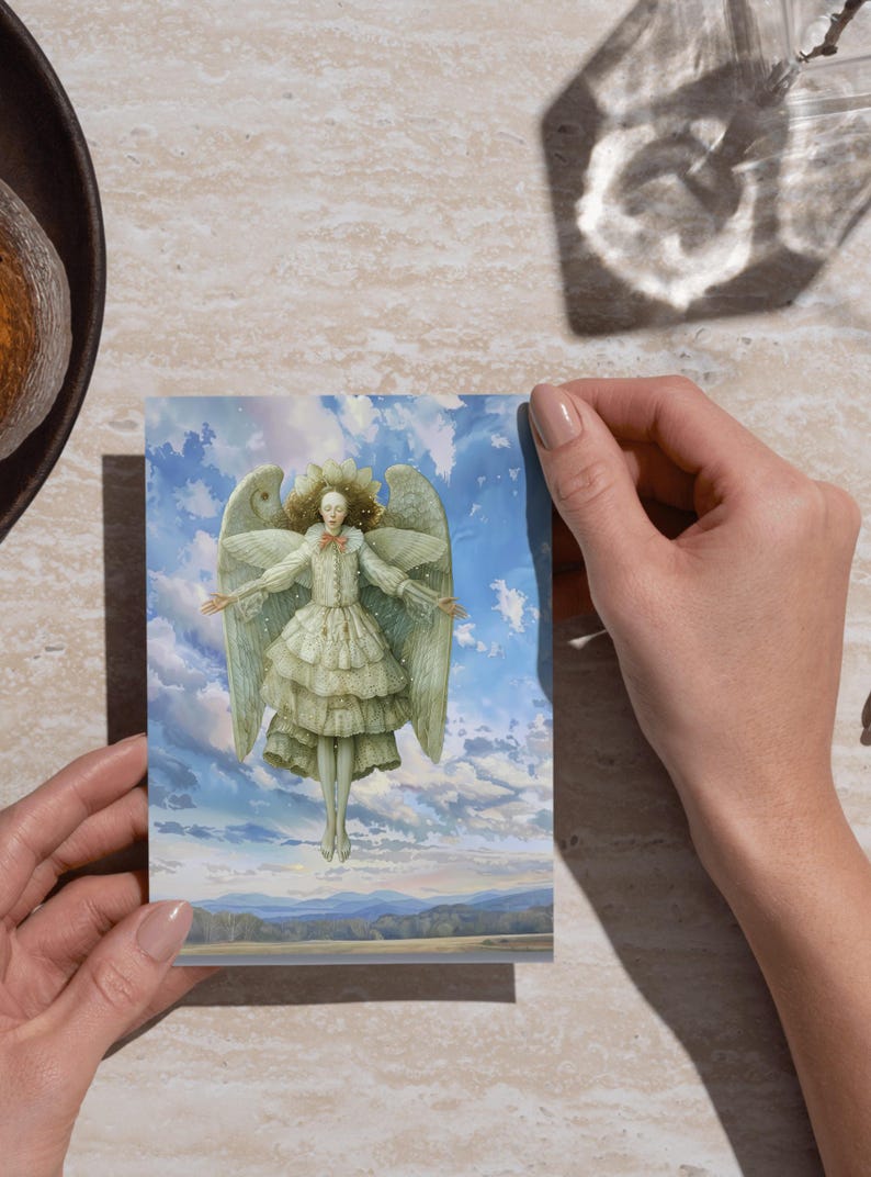 Hands holding a printed angel postcard over wood, demonstrating print at home use for printable Christmas angel paper dolls