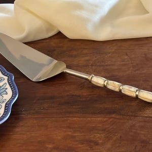 Könnte beinhalten: Ein Set aus drei Keramikbechern mit gesprenkelter, matter Oberfläche. Die Becher sind in Creme-, Hellgrau- und Dunkelgrautönen gehalten. Jeder Becher hat ein schlichtes, minimalistisches Design, perfekt für Kaffee oder Tee.