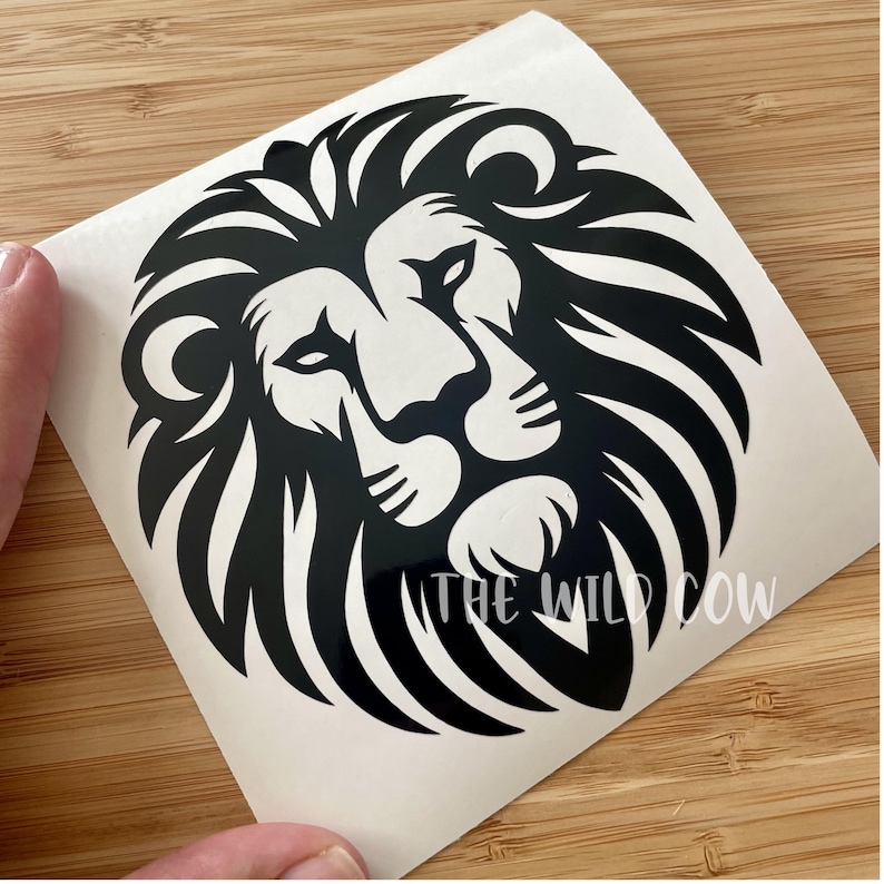 May include: Black and white lion decal with a detailed mane and facial features. The text "THE WILD COW" is printed in white at the bottom. The decal is on a white backing.