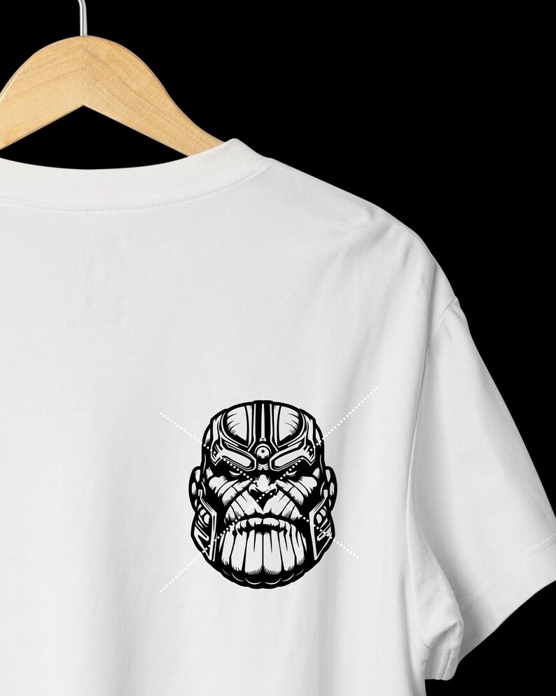 May include: White t-shirt featuring a black and white graphic of a character's face. The design is a detailed illustration with strong lines and shading, creating a bold visual impact. The shirt is hanging on a wooden hanger.