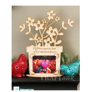 May include: Wooden picture frame with a cutout design of flowers and a pot. The frame has the text "Mothers plant the seeds of love that bloom forever".