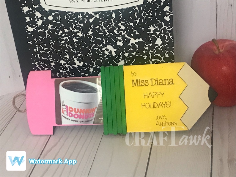May include: A yellow pencil-shaped gift tag with the text "to Miss Diana Happy Holidays! love, Anthony" and a green and pink background. The tag is decorated with a Dunkin' Donuts gift card.