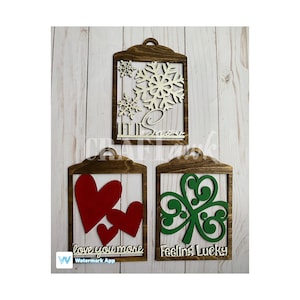 May include: Three wooden signs with cutouts and text. The first sign has a snowflake cutout and the text "Let it Snow". The second sign has a heart cutout and the text "Love you more". The third sign has a shamrock cutout and the text "Feeling Lucky".