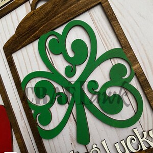 Pu&ograve; includere: Un cartello di legno con un trifoglio verde ritagliato e il testo "Feeling Lucky" in lettere bianche.