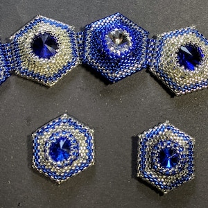 May include: A beaded jewelry set featuring a bracelet and matching earrings. The bracelet and earrings have a hexagonal design with blue and silver beads surrounding a central crystal. The bracelet has a silver clasp.