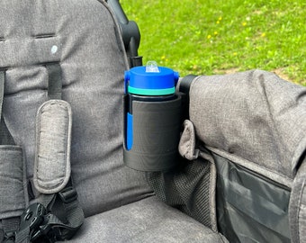 May include: A gray stroller with a blue and green water bottle holder attached to the side. The holder is made of plastic and has a black strap.