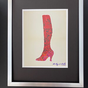 Puede incluir: Una impresión enmarcada de un zapato de tacón alto rojo y rosa con un patrón floral. La impresión está firmada "Andy Warhol".