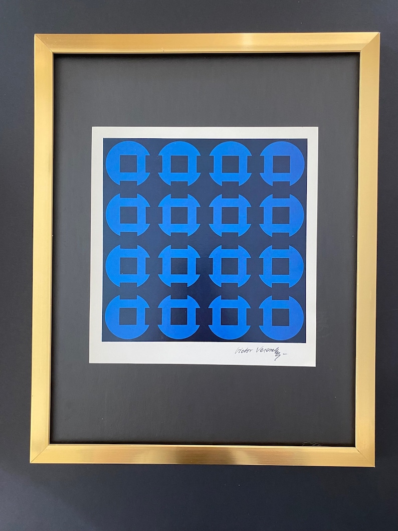 May include: A framed print of a geometric abstract design with a blue and black color scheme. The print is signed "Victor Vasarely".