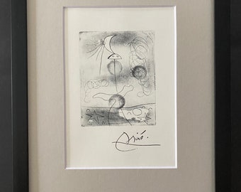 May include: A black and white abstract drawing by Joan Miró, signed in the bottom right corner. The drawing features a crescent moon, stars, and swirling lines.
