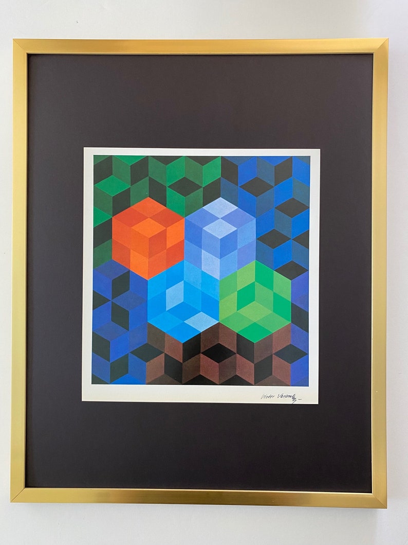 K&ouml;nnte beinhalten: Ein gerahmter Druck eines geometrischen abstrakten Kunstwerks mit einem farbenfrohen Muster aus W&uuml;rfeln in Blaut&ouml;nen, Gr&uuml;n, Orange und Braun. Der Druck ist signiert mit "Victor Vasarely".