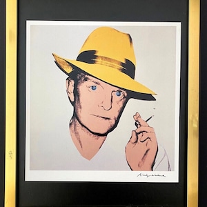May include: A colour screen print of a man wearing a yellow hat and holding a cigarette. The man has blue eyes and a pink face. The print is signed "Andy Warhol" in the bottom right corner.