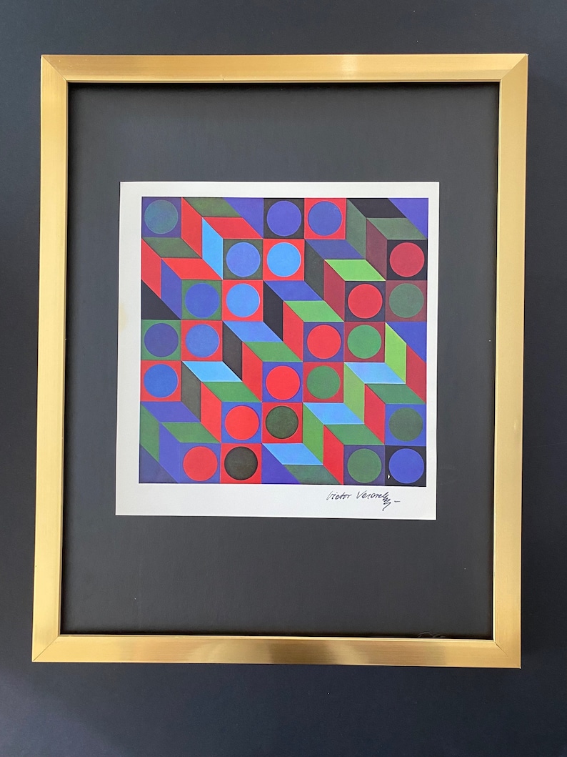 Puede incluir: Una impresi&oacute;n enmarcada de una obra de arte abstracta geom&eacute;trica con un patr&oacute;n colorido de c&iacute;rculos y cuadrados rojos, verdes, azules y negros. La impresi&oacute;n est&aacute; firmada "Victor Vasarely".