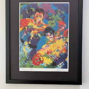 Puede incluir: Una impresión enmarcada de una pintura abstracta colorida que representa a dos boxeadores en acción. La pintura está firmada "LeRoy Neiman" en la esquina inferior derecha.