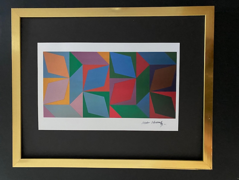 May include: A framed abstract geometric print featuring a colourful design of overlapping diamonds in shades of orange, yellow, green, blue, red, brown, and purple. The print is signed "Victor Vasarely" in the bottom right corner.
