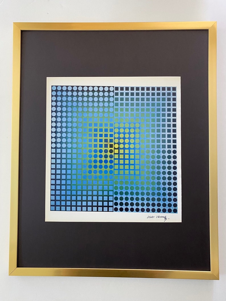 May include: Abstract geometric art print in a gold frame. The artwork features a square design with a grid pattern of blue, green, and yellow circles and squares. The print is matted with a black border.