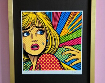 May include: A framed print of a woman with blonde hair in a pop art style. She is wearing a red and yellow polka dot shirt and has a tear running down her cheek. The background is a colorful explosion of red, yellow, blue, and green.