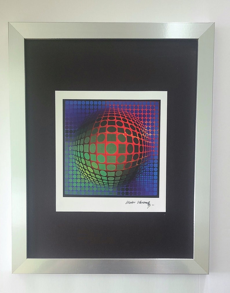 Puede incluir: Una impresi&oacute;n enmarcada de una obra de arte abstracta y colorida de ilusi&oacute;n &oacute;ptica que presenta una esfera hecha de cuadrados rojos, verdes y azules. La obra est&aacute; firmada "Victor Vasarely".