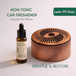 May include: A wooden car air freshener with a cedar essential oil diffuser and a small bottle of cedar freshener. The bottle is labeled with the words "Breathe & Restore" and "100% Natural Essential Oils". The product is advertised as "Non-Toxic" and "Lasts 90 Days".