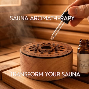 May include: A cylindrical wooden sauna aromatherapy diffuser with a perforated top, featuring the text SAUNA AROMATHERAPY and TRANSFORM YOUR SAUNA. A glass dropper dispenses liquid into the center, while a brown glass bottle labeled BREATHE RESTORE sits nearby.
