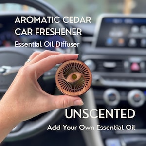 May include: A round, wooden car air freshener and essential oil diffuser featuring a radial, fan-like cutout pattern. The text on the image reads: AROMATIC CEDAR CAR FRESHENER, Essential Oil Diffuser, UNSCENTED, Add Your Own Essential Oil.