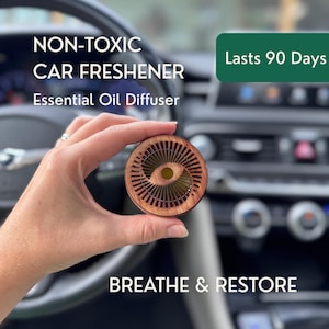 May include: A circular wooden car freshener and essential oil diffuser with a radial slatted design and a central opening. The text reads: NON-TOXIC CAR FRESHENER, Essential Oil Diffuser, Lasts 90 Days, and BREATHE & RESTORE.
