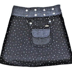 May include: A black wrap skirt with a white letter pattern and a contrasting gray waistband. The skirt features a pocket with a textured gray fabric and silver hardware. The skirt is designed to wrap around the waist and fasten with buttons.