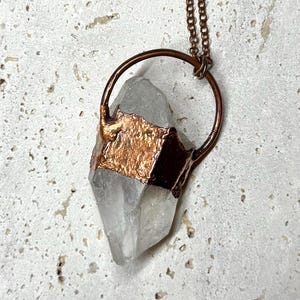 Punta de cristal de cuarzo grande engastada en cobre puro con textura rústica.