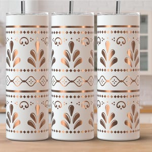 以下が含まれることがあります： 銅色の花柄と幾何学模様の白い断熱タンブラー3個。 デザインには、様式化された葉、ひし形、線が含まれています。 各タンブラーには、銀色のストローと蓋が付いています。