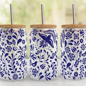 May include: Three glass tumblers with wooden lids and stainless steel straws. The tumblers are decorated with a blue floral and bird pattern on a white background. The design includes flowers, leaves, and birds.