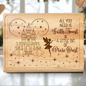 Könnte beinhalten: Rechteckiges Schneidebrett aus hellem Holz mit einem Märchenschloss-Design und dem Schriftzug "ALL YOU NEED IS Faith, Trust & A LITTLE BIT OF Pixie Dust". Das Brett hat eine abgeschrägte Kante.