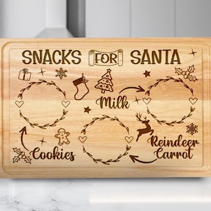 Op de afbeelding: Een rechthoekige houten snijplank met bovenaan de woorden "SNACKS FOR SANTA" gegraveerd. De plank heeft gegraveerde illustraties van een cadeau, sneeuwvlok, kous, kerstboom, ster, hulst, melk, hart, rendier en wortel.
