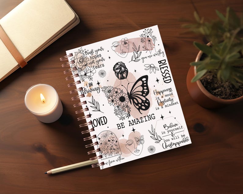May include: A white spiral bound journal with black and white illustrations and inspirational quotes. The quotes include "Trust your hopes not your fears", "I am thriving", "Loved", "Be Amazing", "Blessed", "Happiness is a mood Positivity is a mindset", and "Believe in yourself & you will be unstoppable".