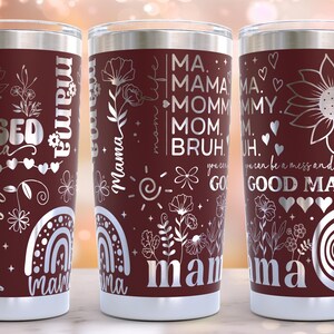 May include: Three stainless steel tumblers with maroon colored bodies and silver lettering. The tumblers feature various designs and text, including "Blessed Mama", "Good Mama", and "Mama".