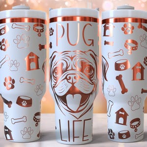 Peut inclure: Trois tasses de voyage en acier inoxydable blanc avec un bord et un motif de couleur cuivre. La tasse de gauche a un motif de patte, d'os et de niche pour chien. La tasse du milieu a un visage de carlin et le texte "PUG LIFE". La tasse de droite a un motif d'os, de patte et de bol pour chien.