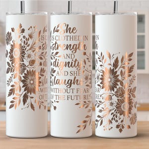 May include: White tumbler with a floral design in shades of brown and copper. The tumbler has the text "She is clothed in strength and dignity and she laughs without fear of the future".